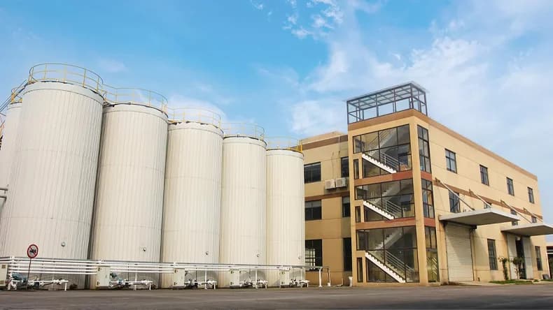 Industrial building and storage tanks under a blue sky